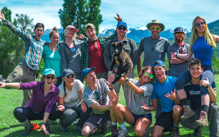 A group of people pose for a photo in front of mountains. 